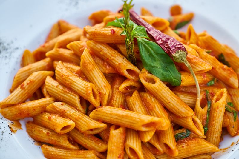 Baked penne arrabiata with spicy tomato sauce and herbs